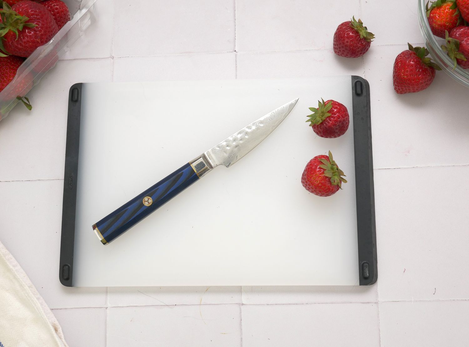 cangshan paring knife on a white plastic cutting board with strawberries