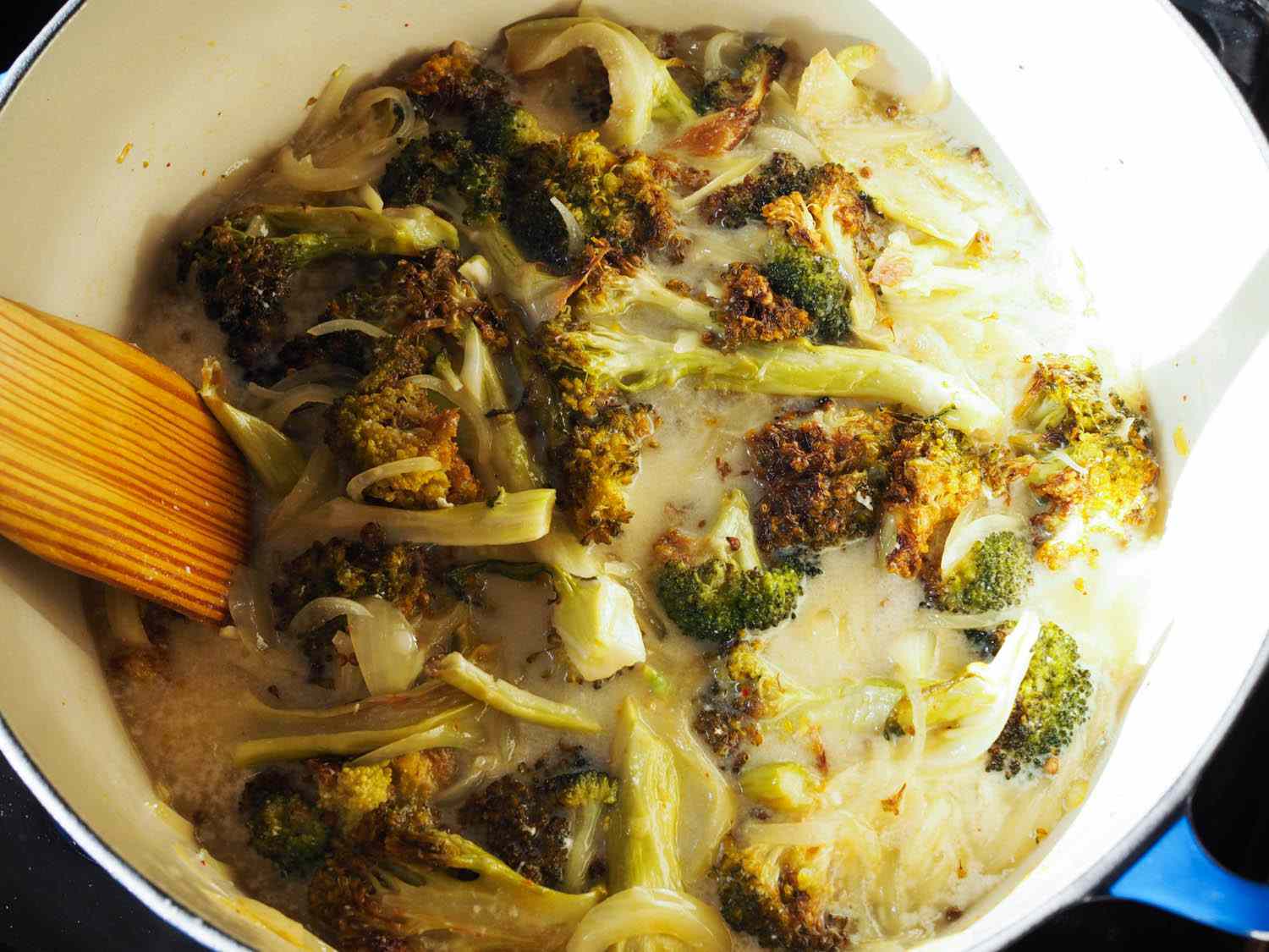 The roasted broccoli is added to the pot with the onions and garlic.