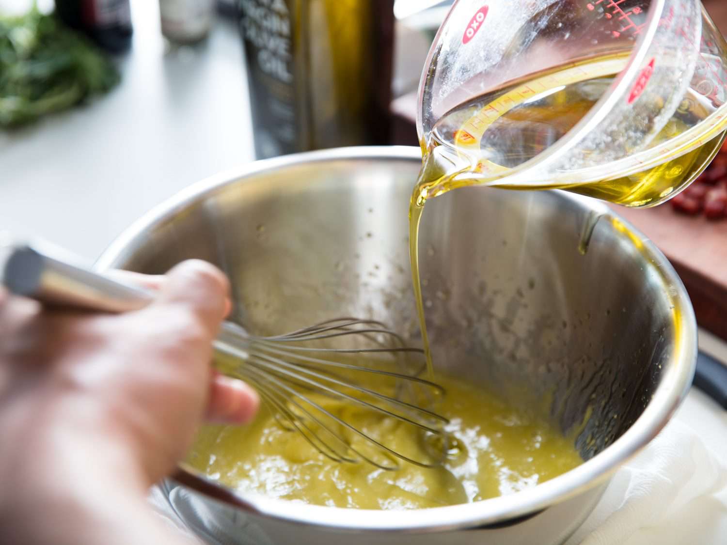 Drizzling in oil while hand-whisking mayonnaise.
