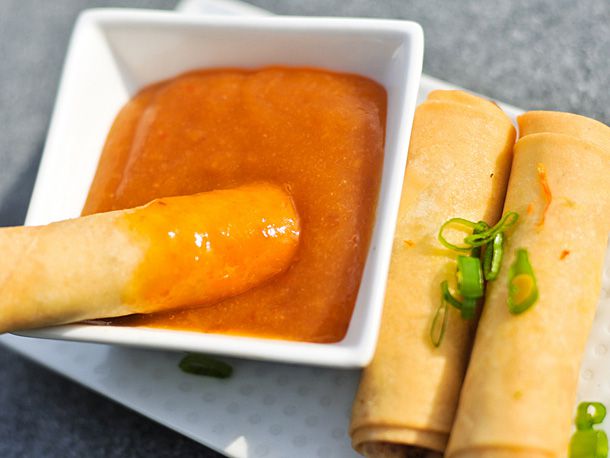 Fried egg roll being dipped in homemade duck sauce.