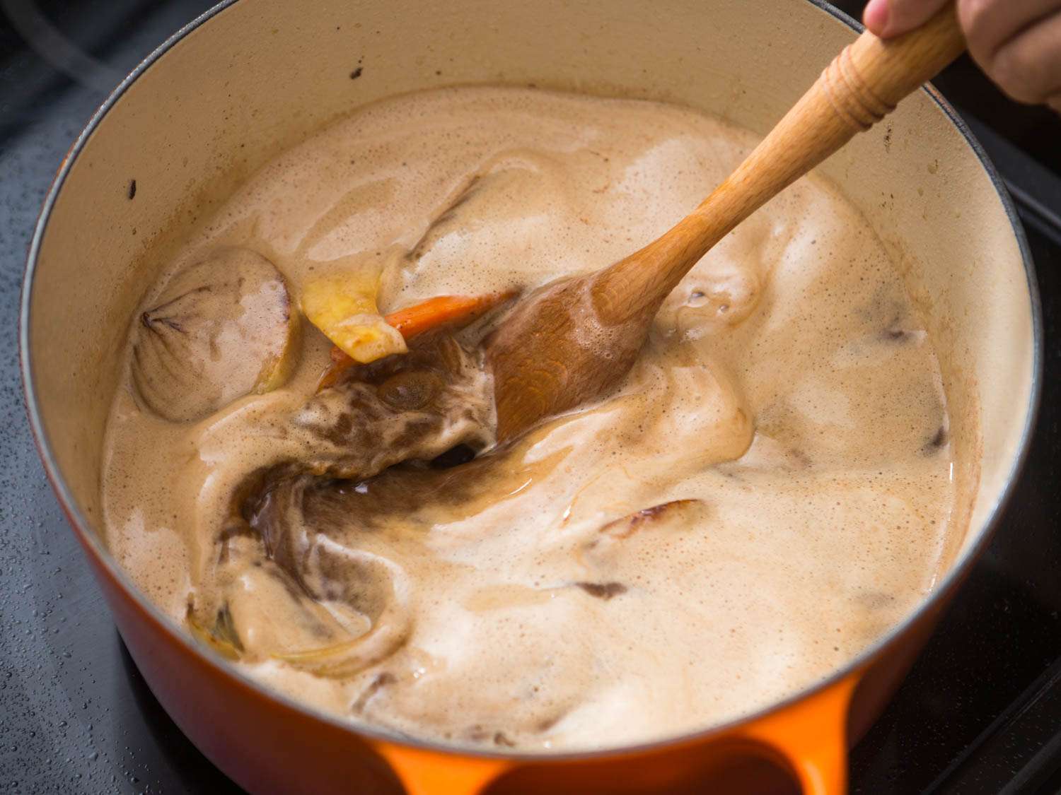 Using wooden spoon to scrape up bits from bottom of pot