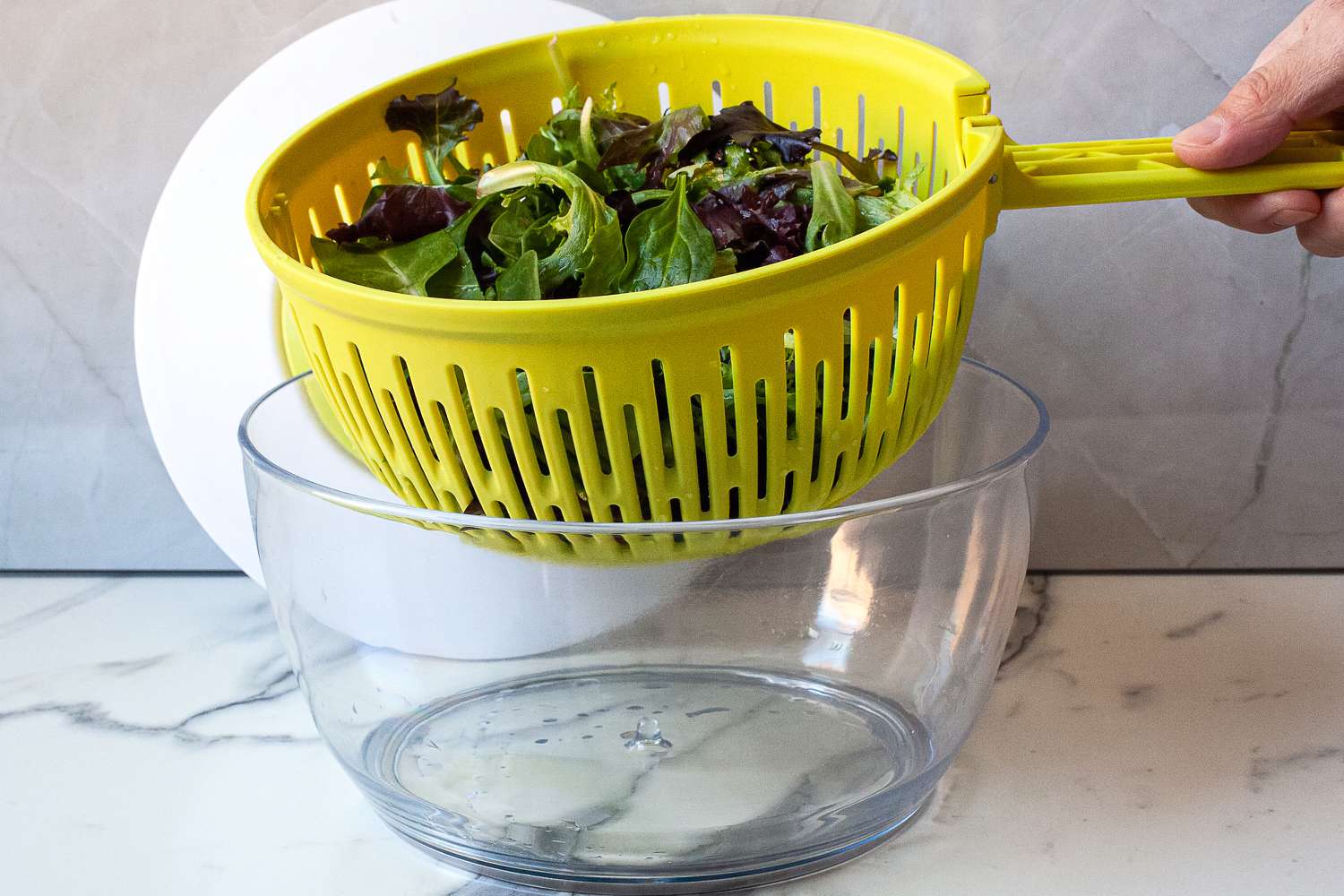 a person removing the basket of greens on the chef'n spinner