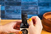 Hands opening a bottle by peeling off the seal surrounding its neck