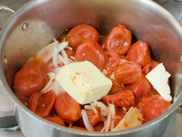 A pot of whole tomatoes, onions, and butter for homemade butter chicken sauce