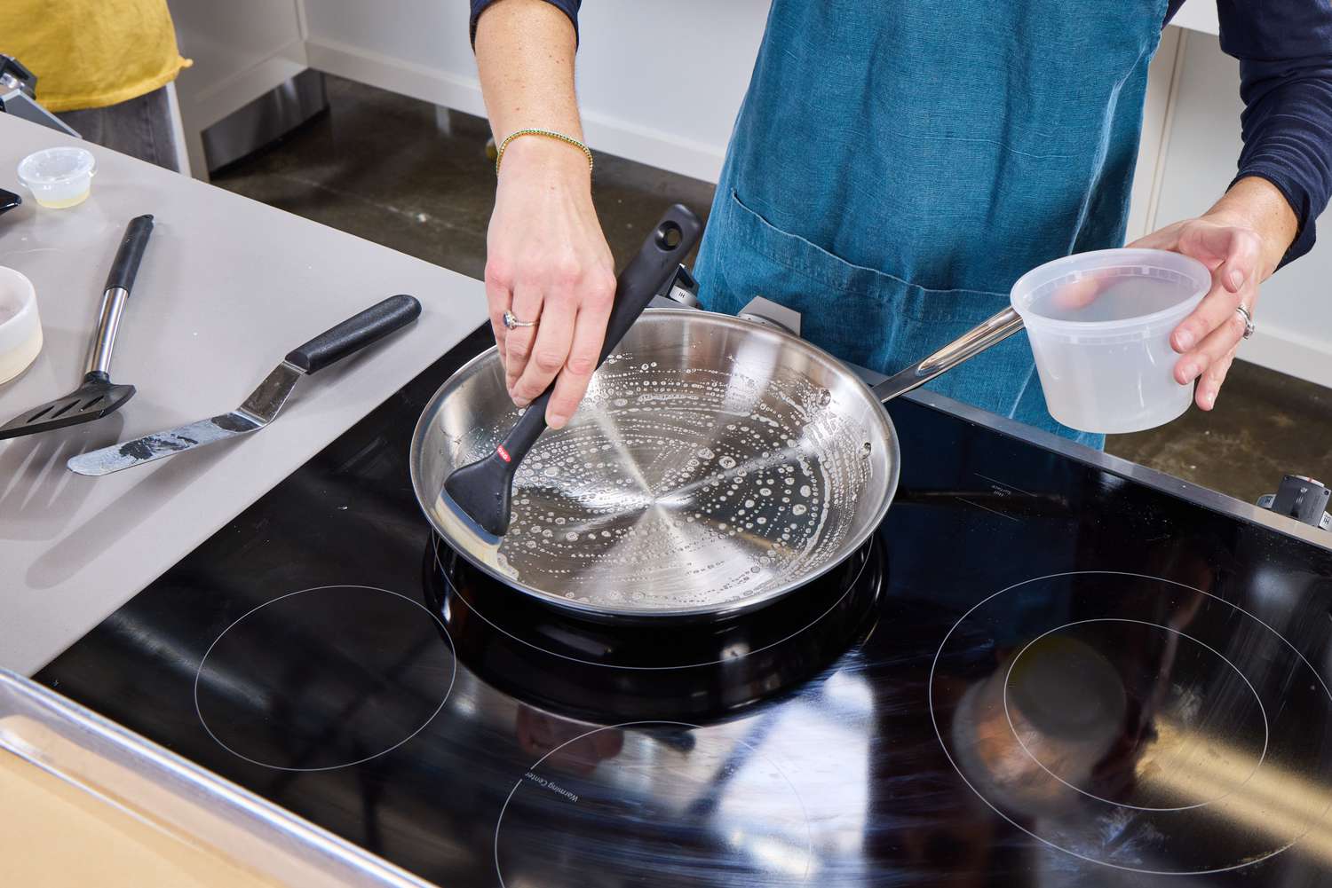 A person greases the All-Clad D3 Stainless-Steel 12-Inch Fry Pan with oil