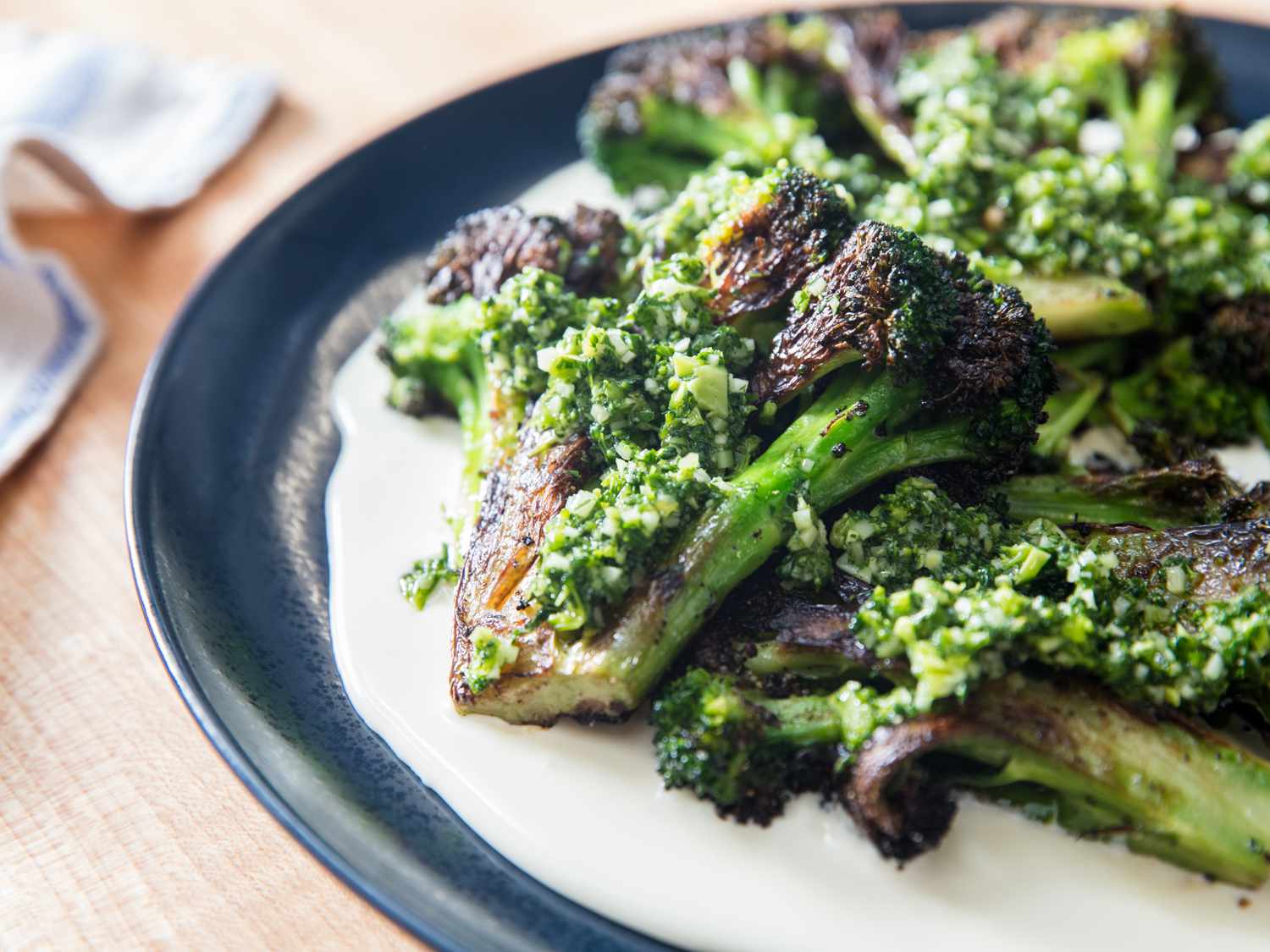 A plate of charred broccoli over a Taleggio cheese sauce, garnished with gremolata.