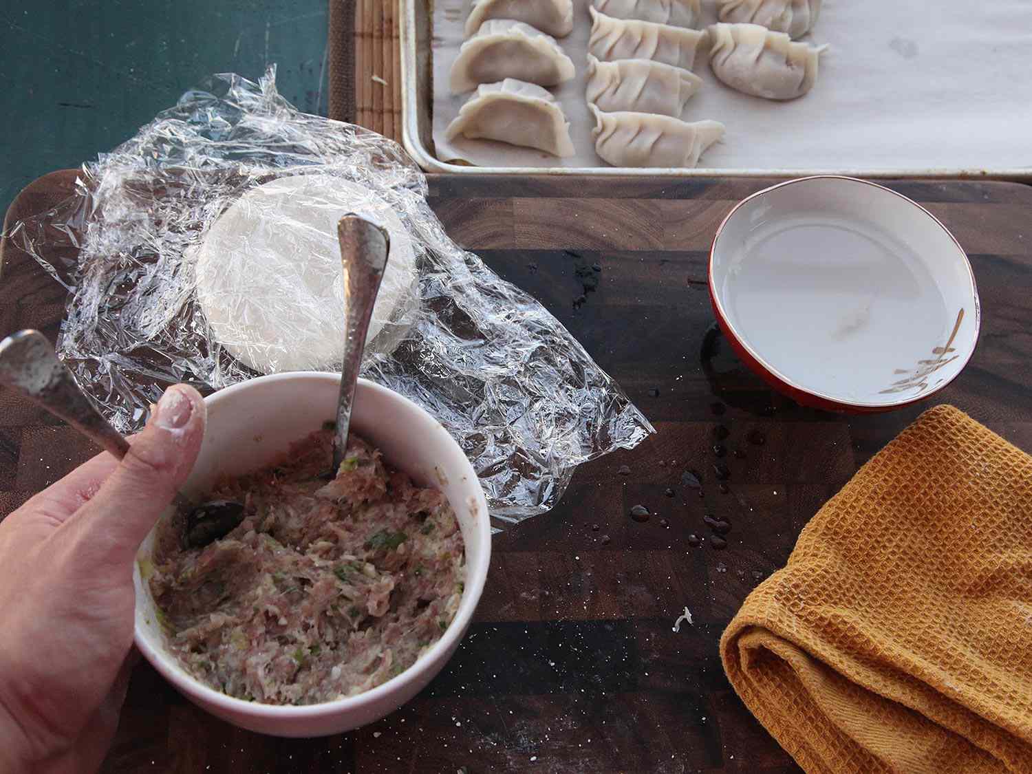 Dumplings being filled and placed on a baking sheet. 