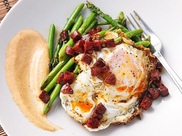 Overehad closeup of sautéed asparagus with chorizo, fried eggs, and smoked-paprika allioli.