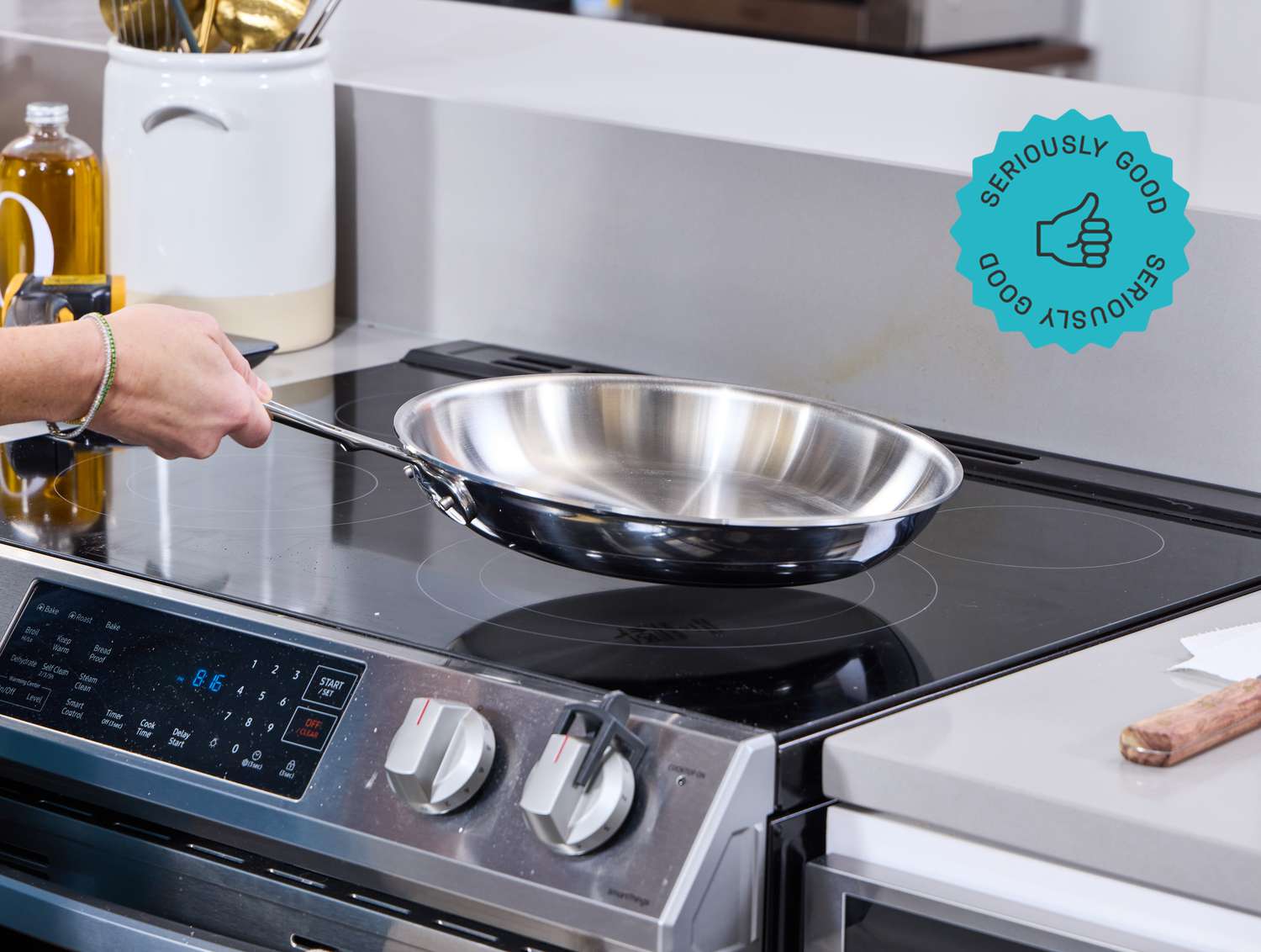 a person lifting the all-clad skillet from an electric stovetop