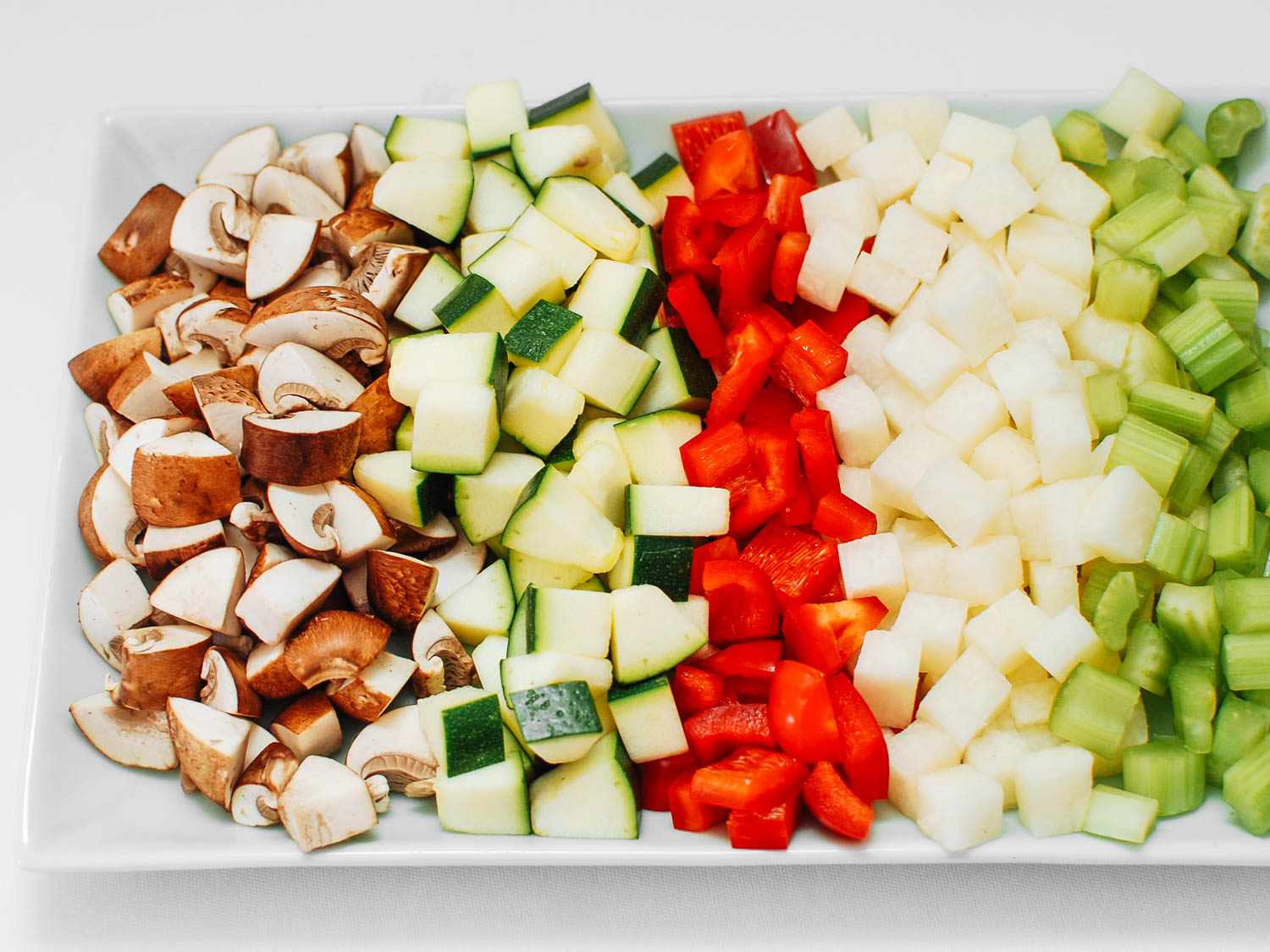 A platter of diced vegetables to stir-fry in cashew chicken ding: mushroom, zucchini, red bell pepper, jicama, and celery.
