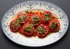 A platter of Vietnamese-style pork-stuffed tomatoes garnished with herbs