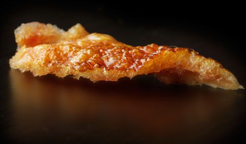 Crisp, cooked pork skin on black background.