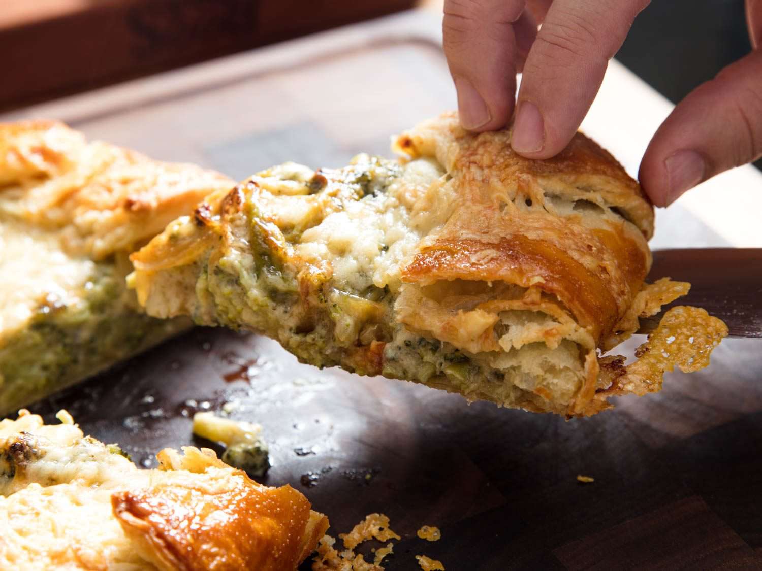 Picking up a wedge of broccoli and cheese galette