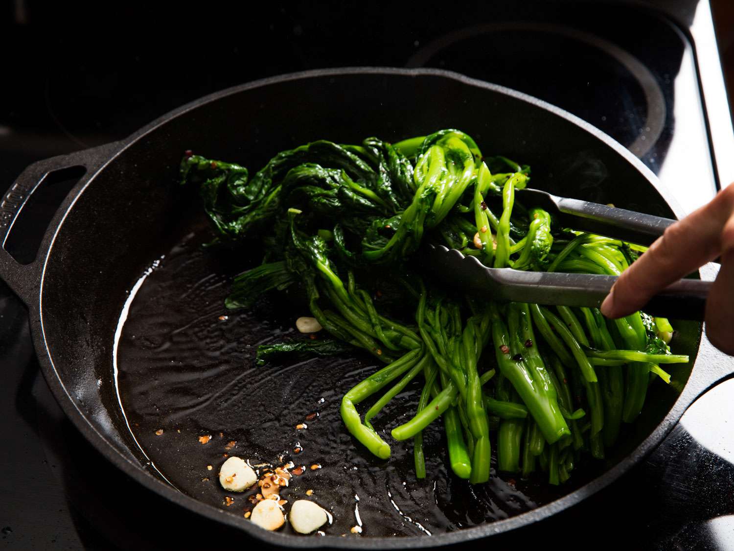 Sautéing broccoli rabe in a skillet with garlic and red pepper flakes.