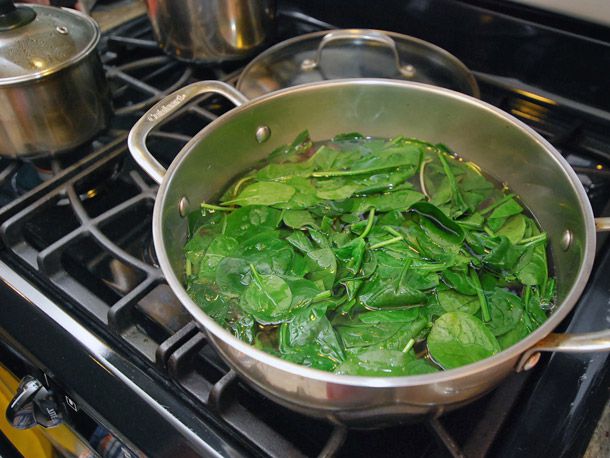 Bright green spinach simmering in a pot of salted water.
