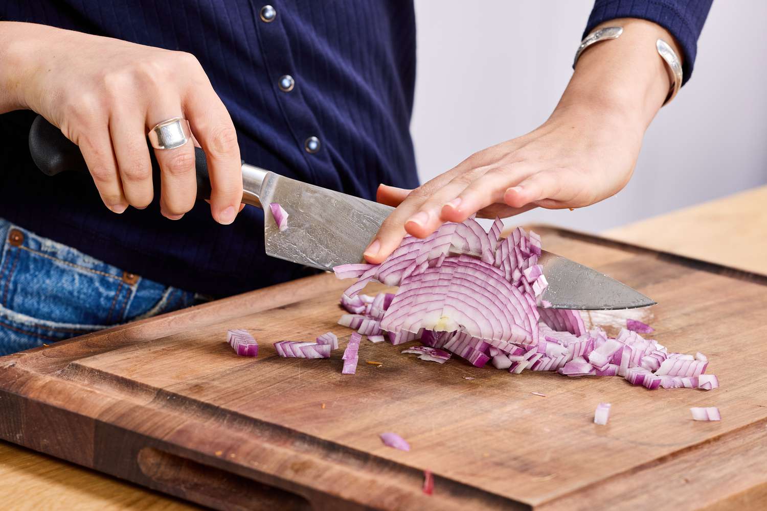 A person dicing a red onion with the Mercer Culinary 8-Inch Genesis Chef's Knife