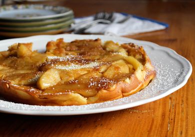 A German pancake with caramelized apples on a white plate