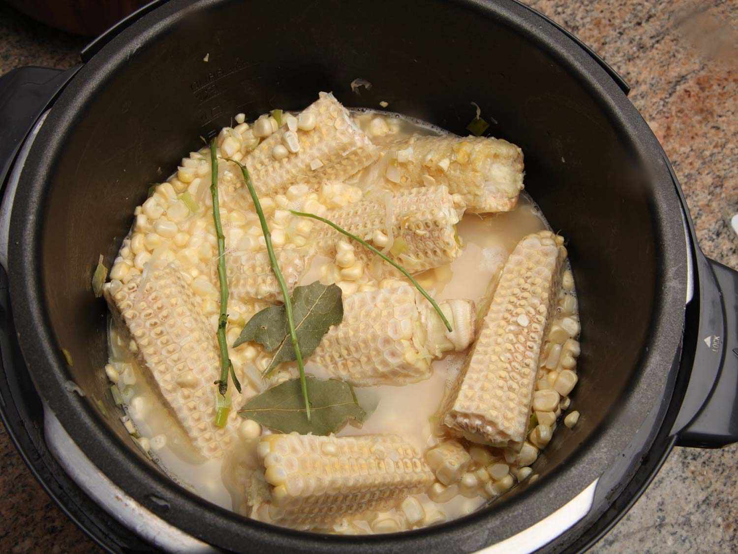 Cut kernels, shaved corn cobs, herbs, and stock in a pressure cooker.