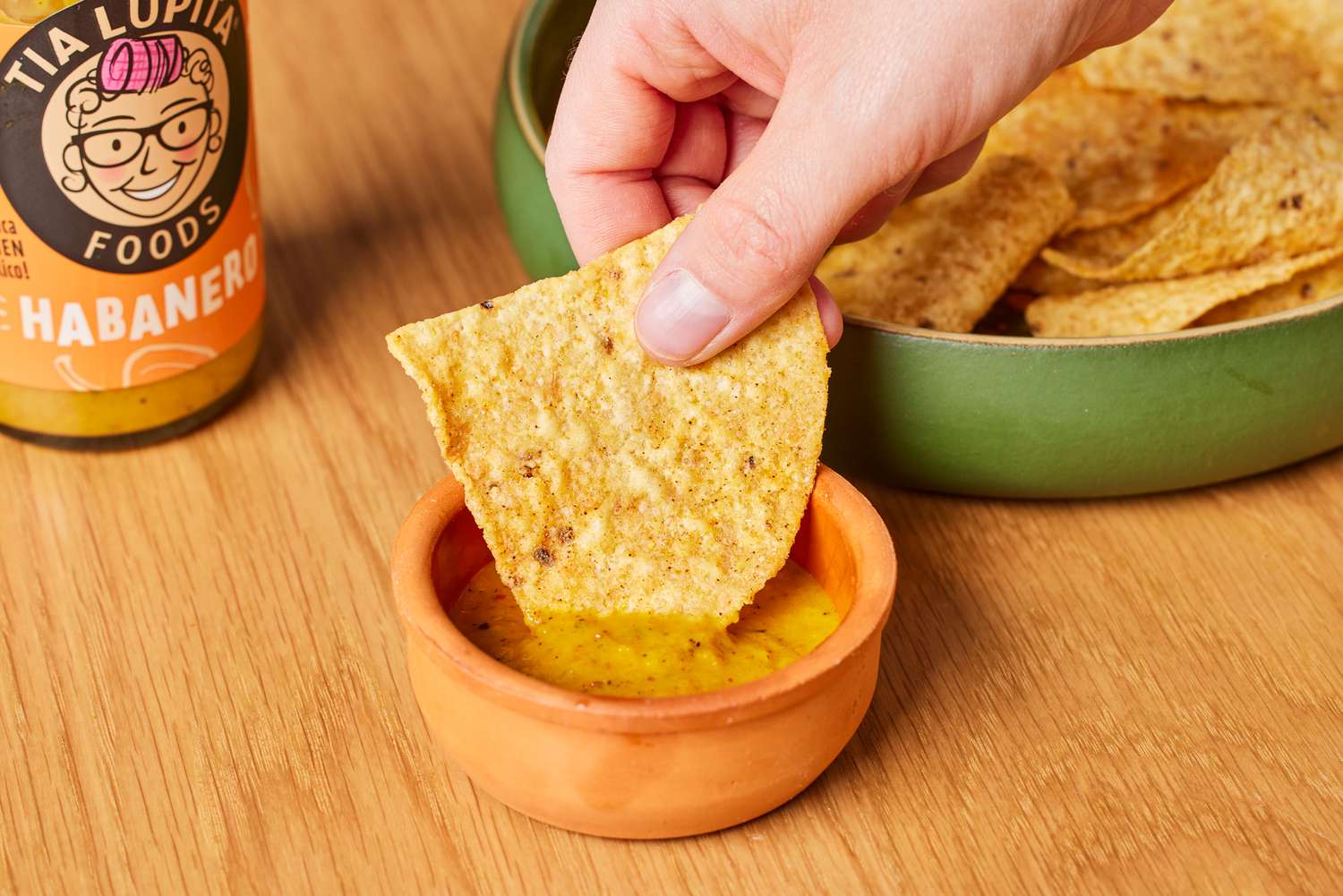 Person dipping chip into Tia Lupita Habanero Hot Sauce
