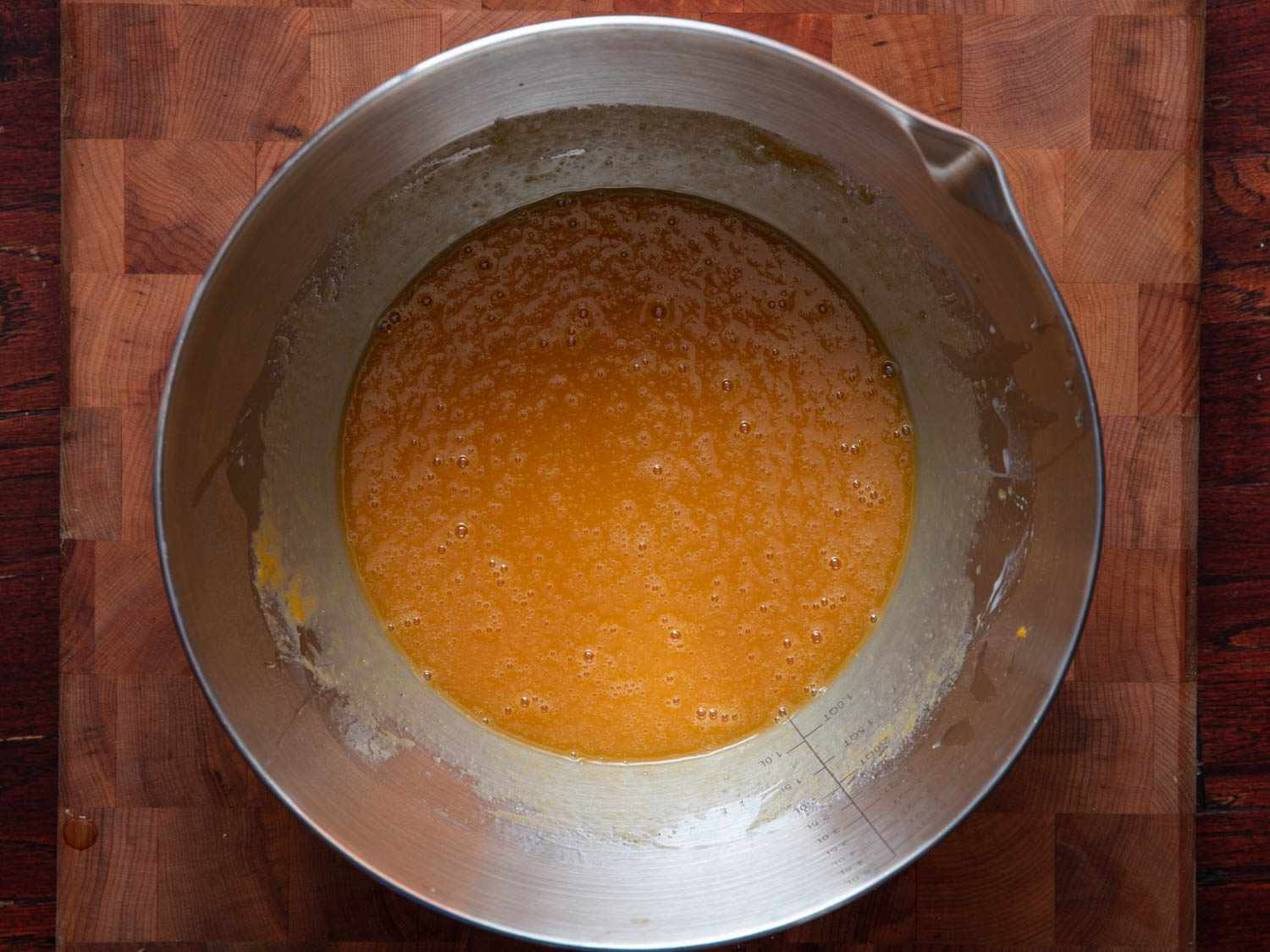 Overhead view of a saucepan containing combined wet ingredients for pumpkin bread: pumpkin puree, vegetable oil, and sugar.