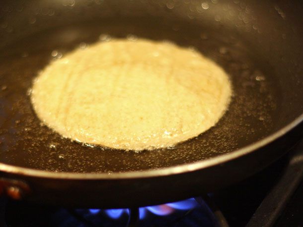 Pan-frying a corn tortilla in a skillet.