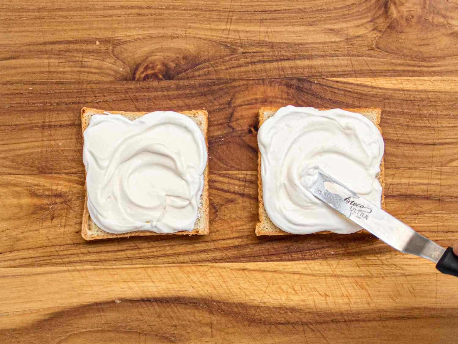 Overhead view of spreading whipped cream on sandwich