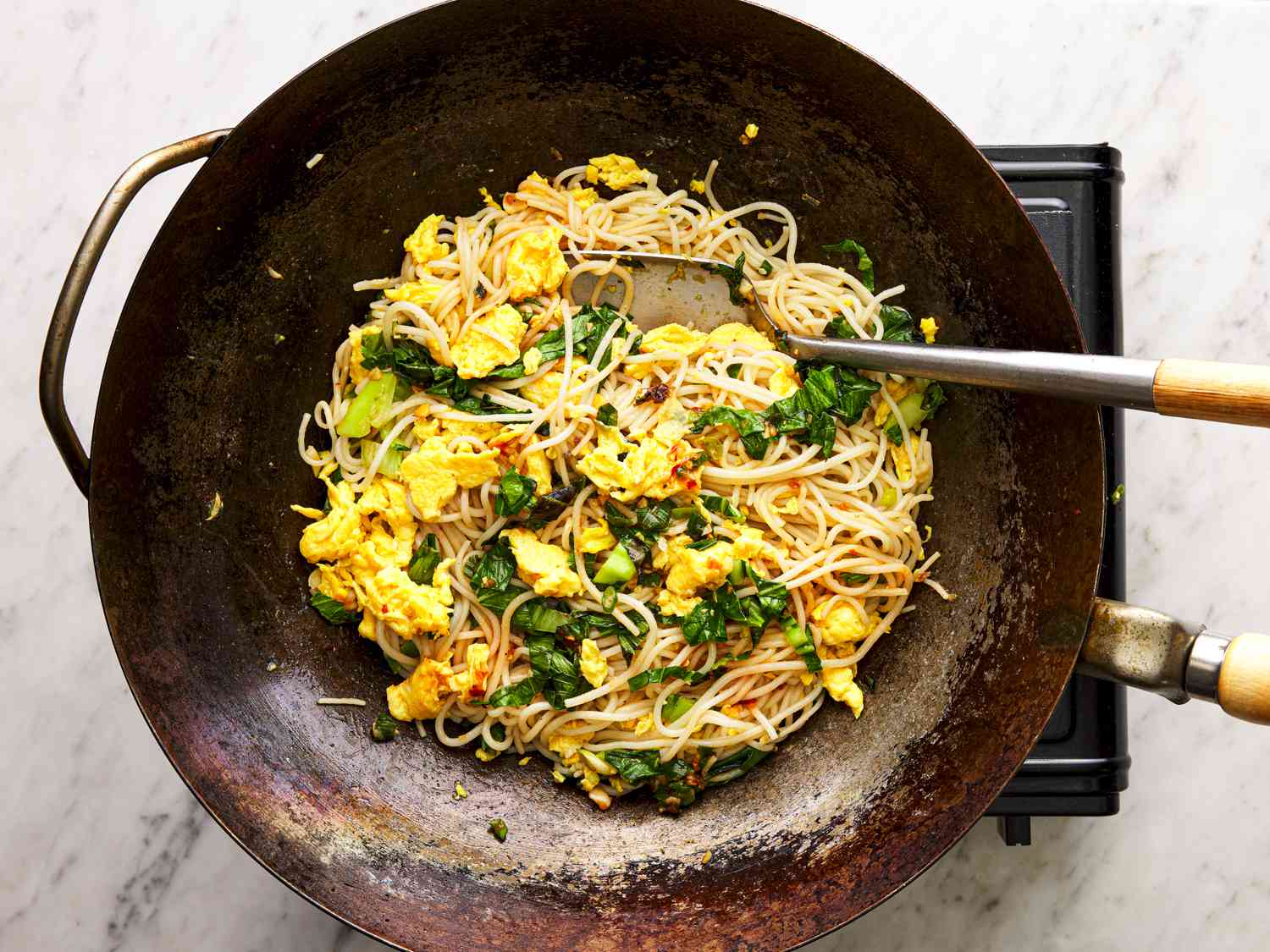 Noodles, eggs and greens combined in a wok