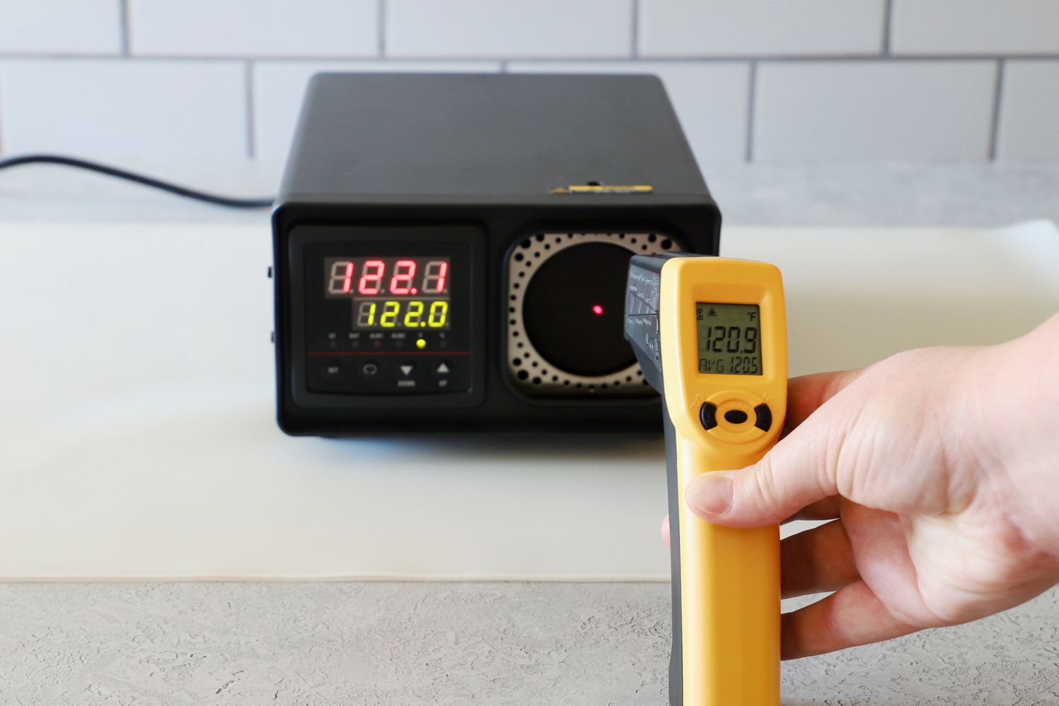 a person pointing an infrared thermometer at a calibration box