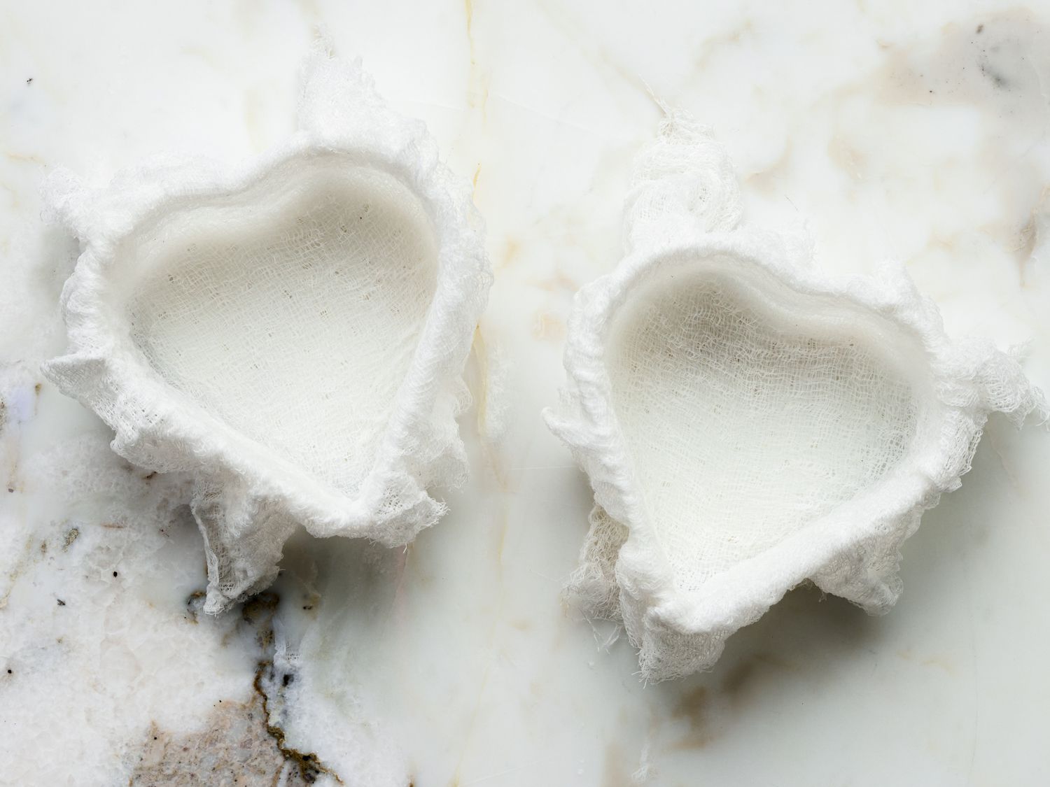 Overhead view of heart shaped molds lined with cheesecloth