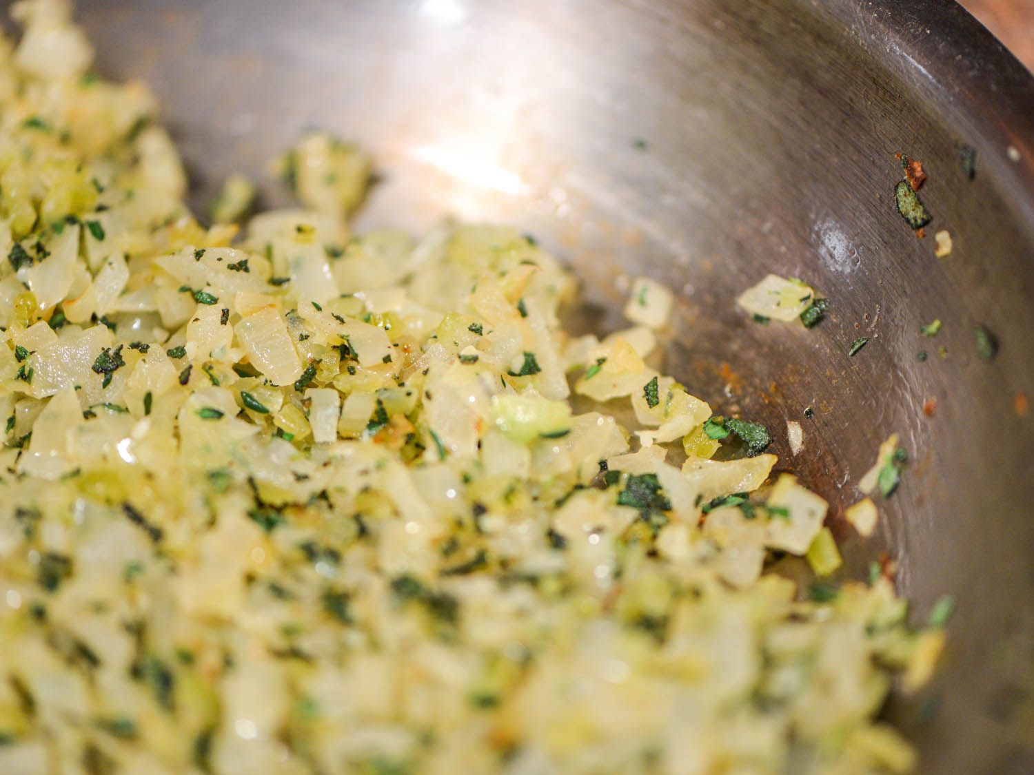 Bowl of sauteed chopped onion and celery with herbs.