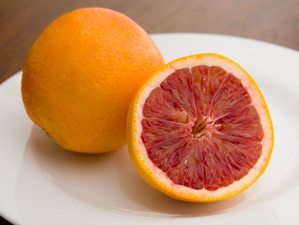 Closeup of a halved blood orange on a cutting board.