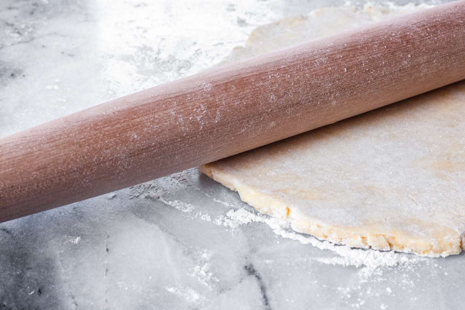 J.K. Adams Maple French Rolling Pin resting on a sheet of dough on a floured surface