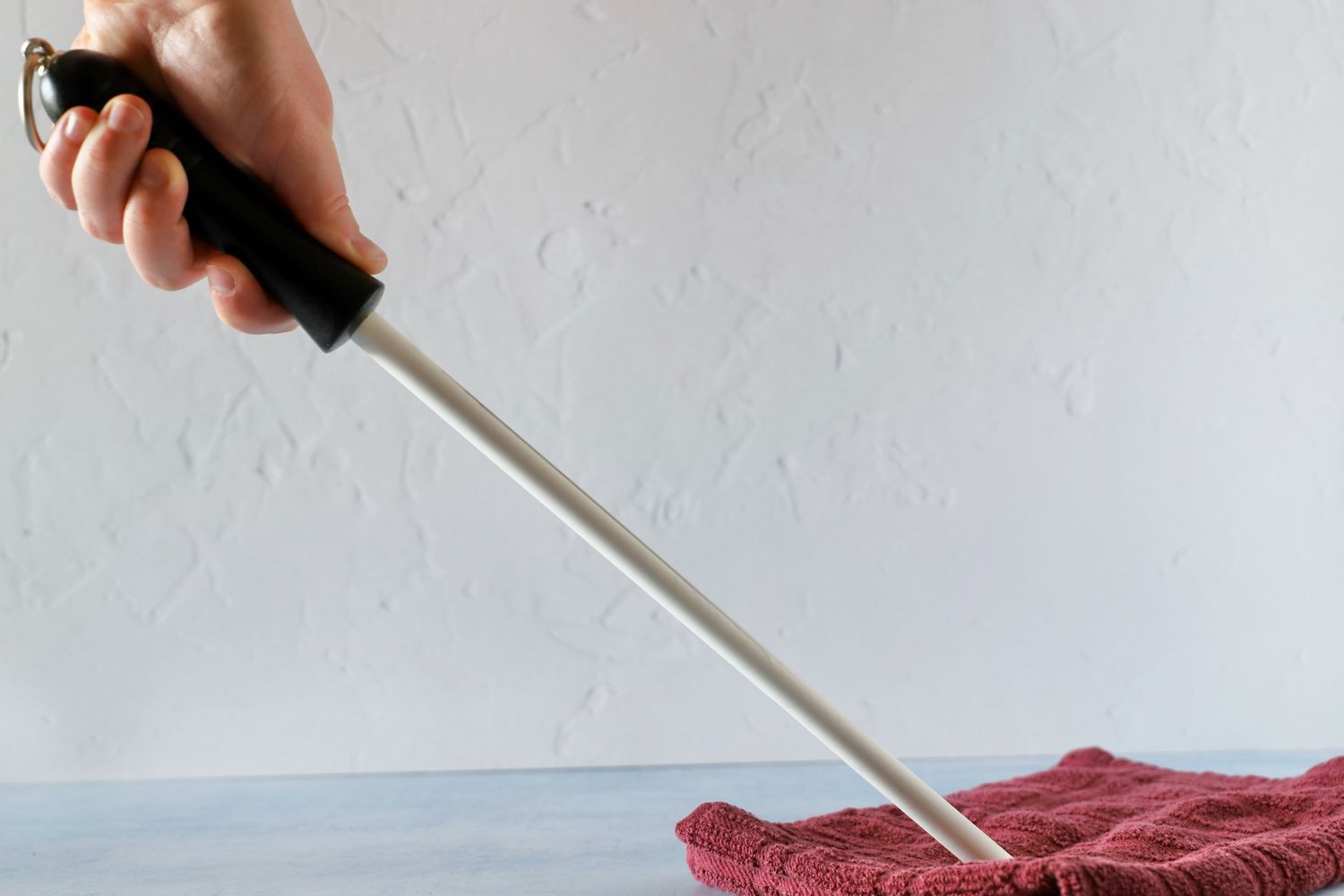 A hand holding a knife sharpening rod in a sharpening position