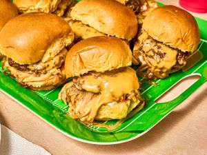 Bright green platter of sliders with overflowing cheese and onions 