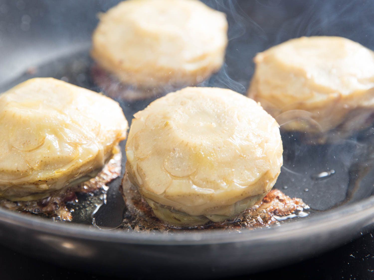The braised artichokes are upended onto their pancetta-covered side and seared in a nonstick skillet.