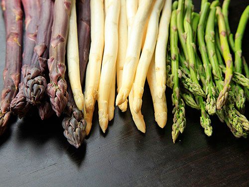 Three types of asparagus in piles next to each other.