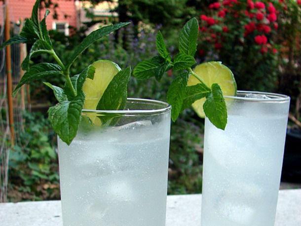 Two cocktails outside, garnished with mint and lime slice.