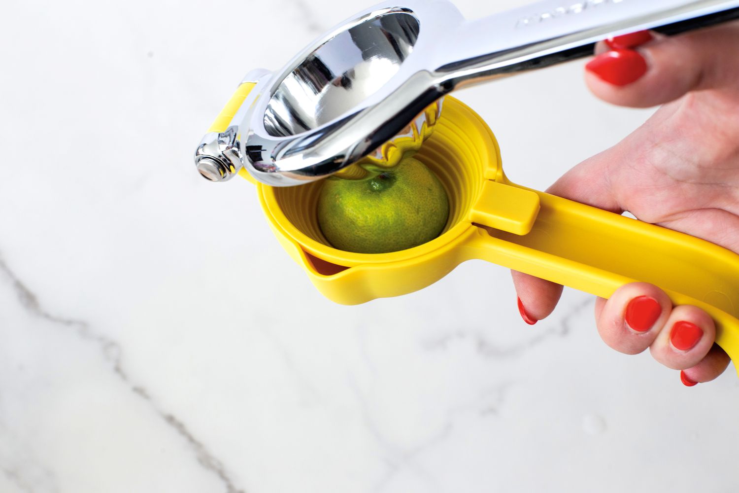 A person juicing a lime with the KitchenAid citrus juicer.