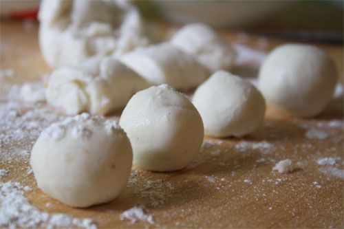Close-up of filled tang yuan lined up on a floured work surface.