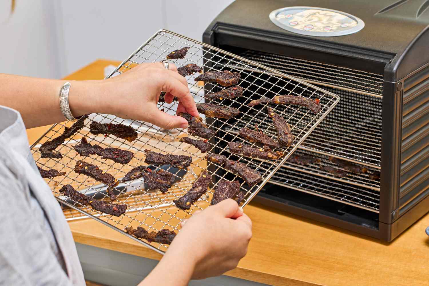 A person holding the tray with food of Samson Silent Dehydrator