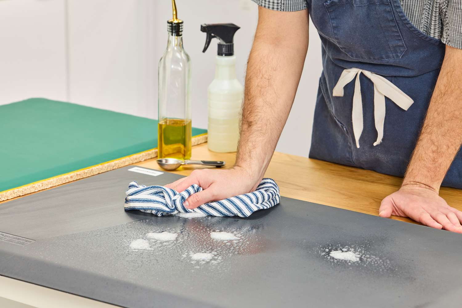 A person wipes cleaning solution off of the WellnessMats Original Anti-Fatigue Floor Mat