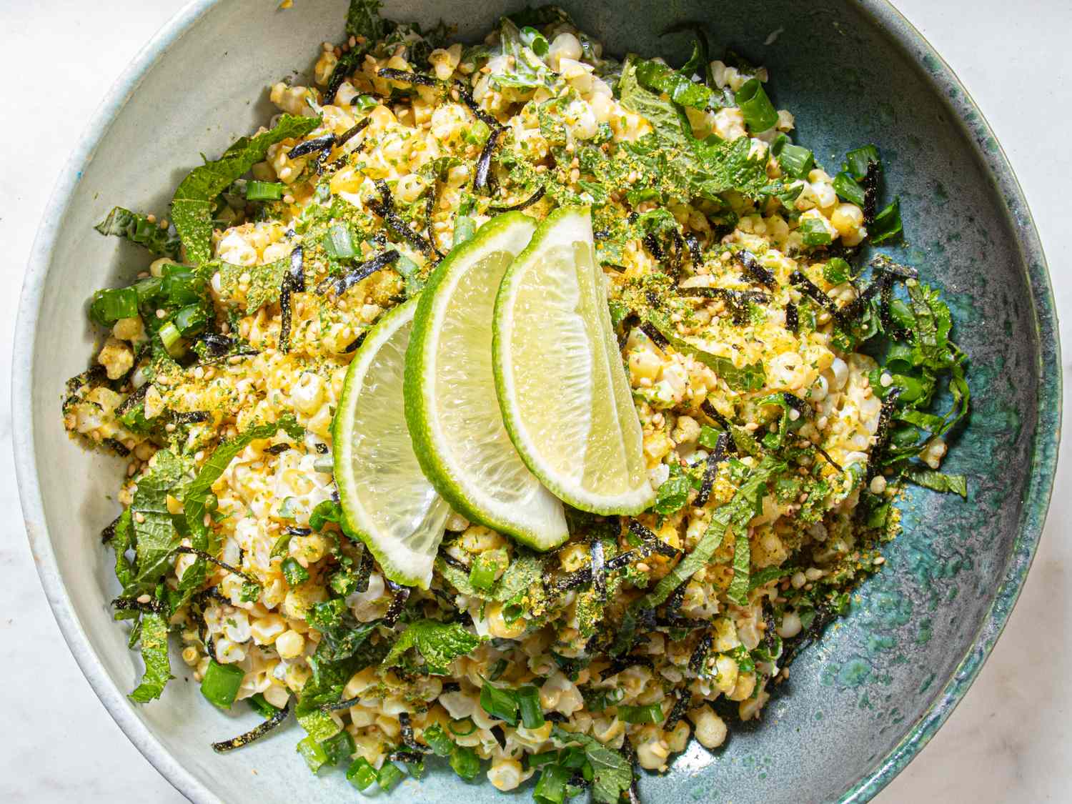 Corn salad topped with lime wedges in a bowl