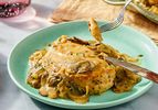 A plate with chicken fricassee served with mushroom sauce a fork lifting a piece of chicken