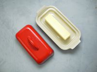 Le Creuset butter dish with stick of butter on bottom dish and lid to the side