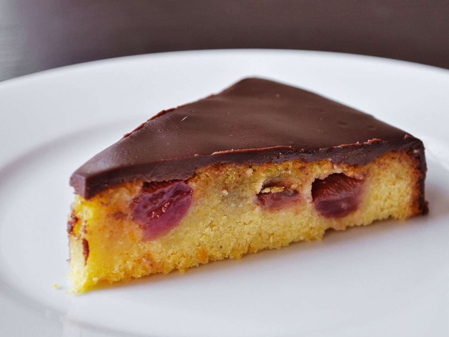 Closeup of a slice of Olive Oil Cake With Roasted Grapes and Ganache