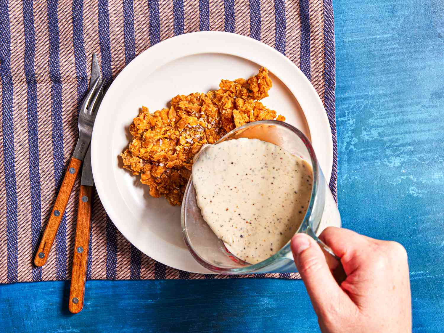 Gravy being poured over chicken fried steak