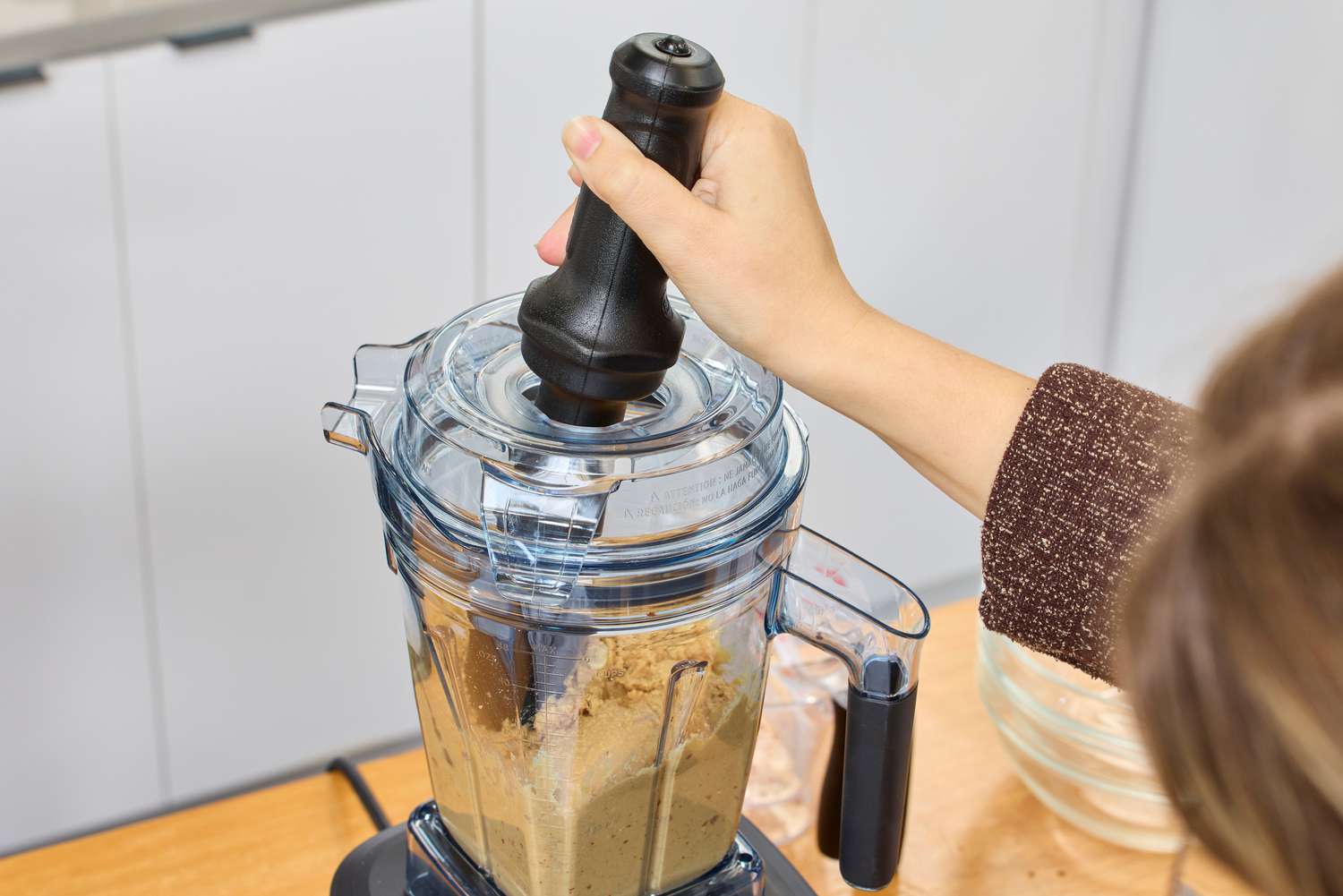 A person using the tamper on the Vitamix Ascent X5 Blender while making peanut butter