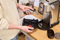 A person assembles the De'Longhi EC900M Dedica Maestro Espresso Machine