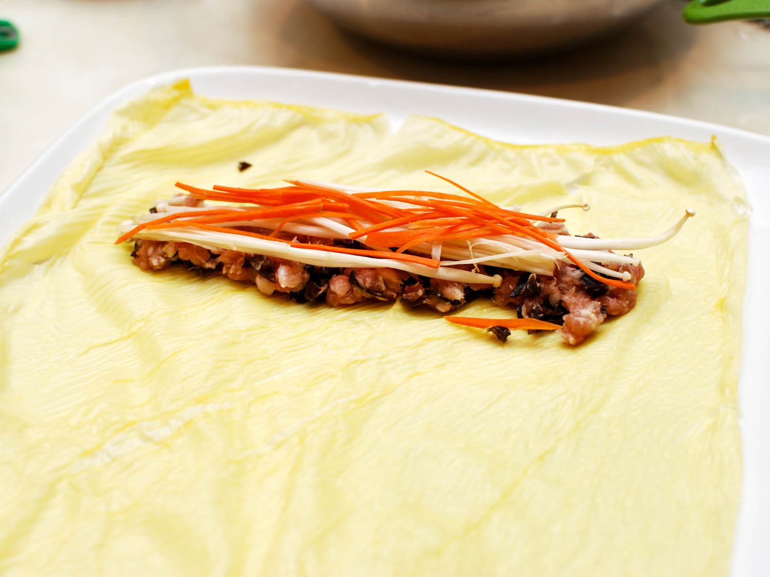 Carrot matchsticks are stacked on top of the filling and enoki mushrooms.