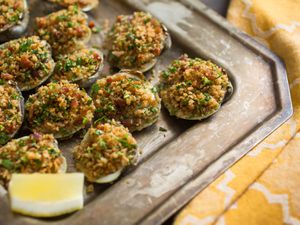 A tray of easy, ultimate Clams Casino with a lemon wedge. 